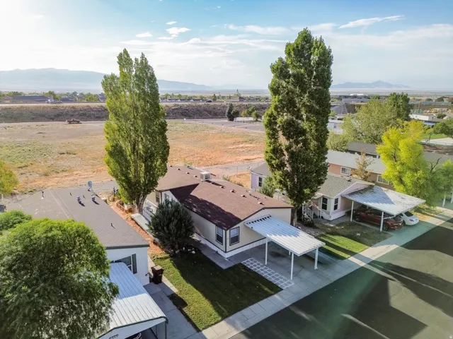 Single-story residence featuring a covered carport, manicured lawn, and mature trees