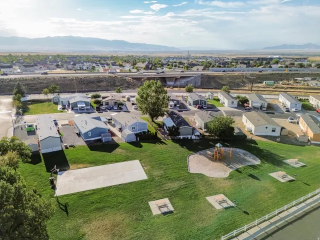 Community green space featuring a playground, concrete activity pad, and picnic areas