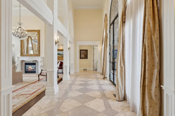 High ceilings, patterned tile flooring, arched windows with decorative ironwork, and a decorative fireplace with an ornate mantel