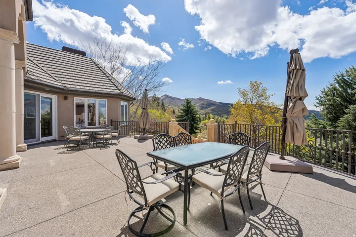 Expansive outdoor patio with a tiled roofline, decorative wrought iron railing, and a columned architectural accent