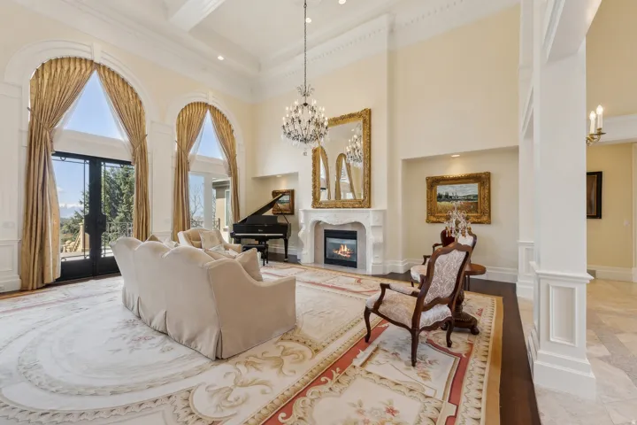 Grand living space with arched windows, a built-in fireplace, intricate ceiling details, and dark wood-finish flooring