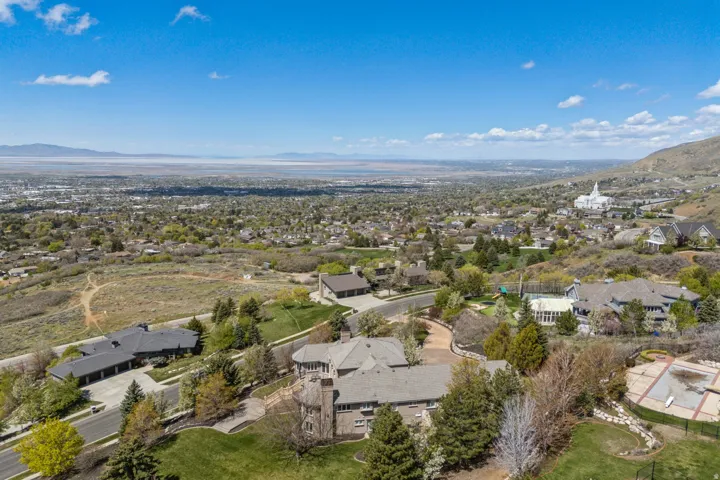 Expansive suburban landscape with distant mountains, featuring a large residential property with mature trees and a paved driveway