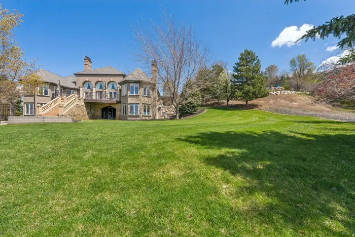 Expansive rear lawn with mature trees and landscaped hillside