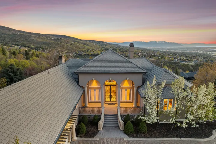 Stucco exterior with a tile roof, double-door entryway, and mature landscaping