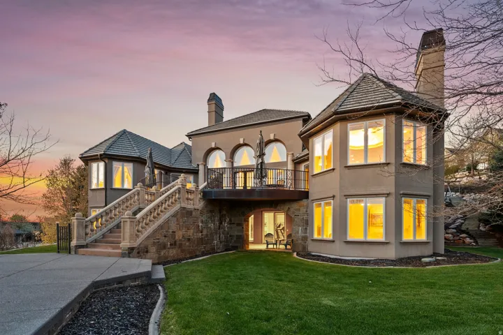 Stucco exterior with a stone foundation, multiple bay windows, an exterior balcony, and stone balustrade stairs