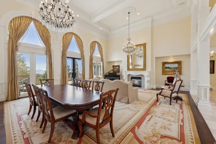Grand living space featuring vaulted ceilings, arched windows with exterior access, a built-in fireplace, and ornate chandeliers