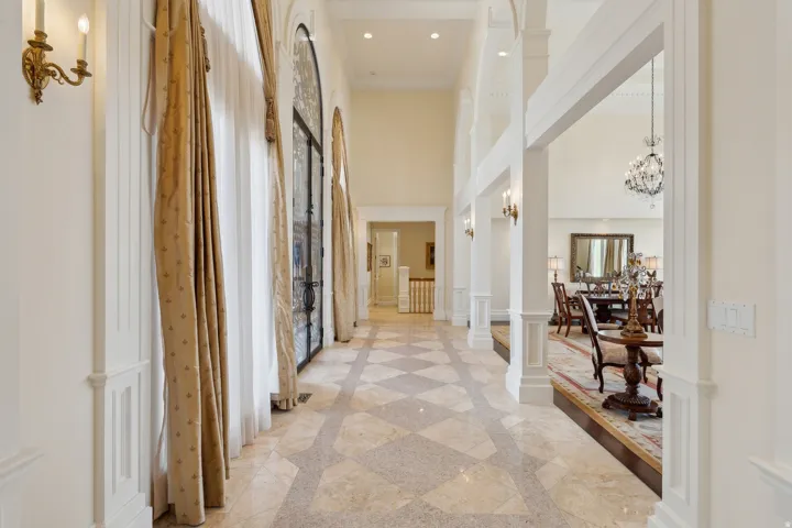 Two-story foyer featuring patterned tile flooring, arched entryways, and decorative wall sconces