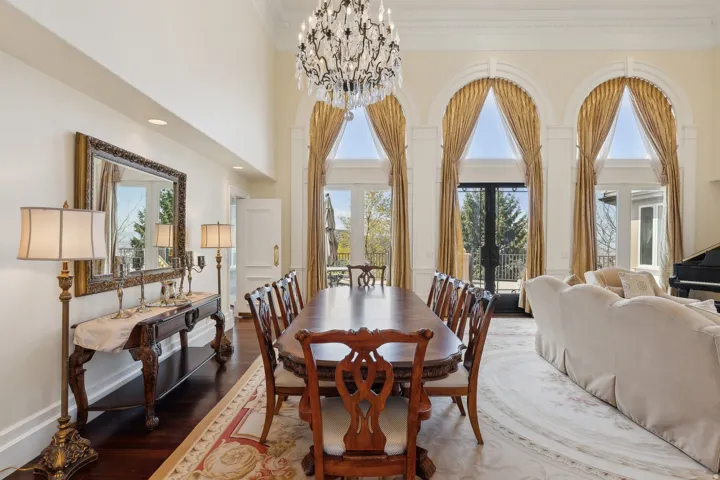 Grand dining area featuring a double-height ceiling, an ornate chandelier, and arched windows