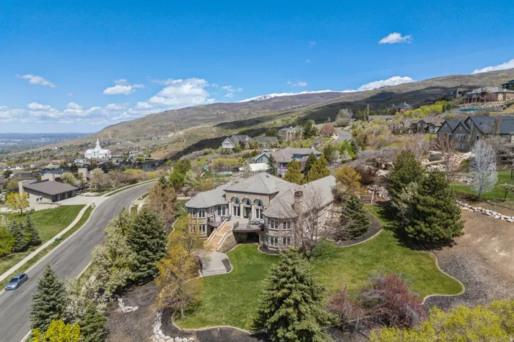 Stone-clad exterior, multi-level structure, paved driveway, mature trees, and landscaped grounds