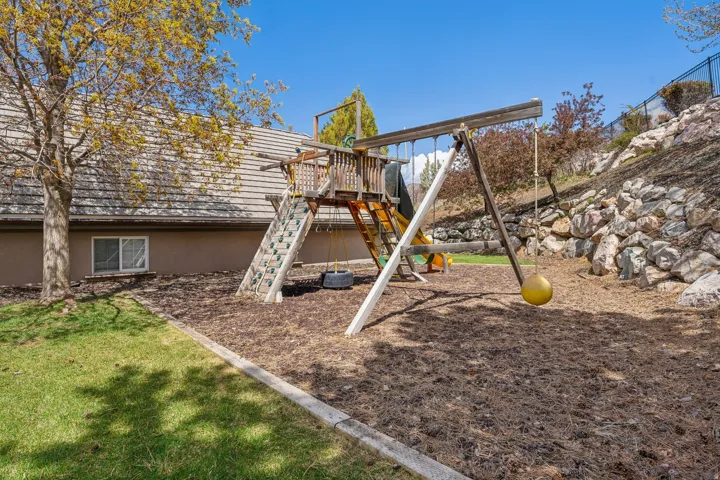 Outdoor play structure with slide and swings, set on a wood chip base