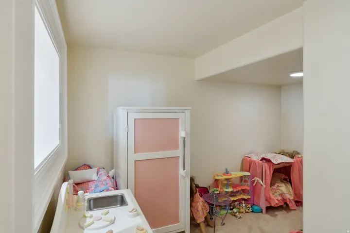 Recessed lighting, wall-to-wall carpeting, and a window with white trim