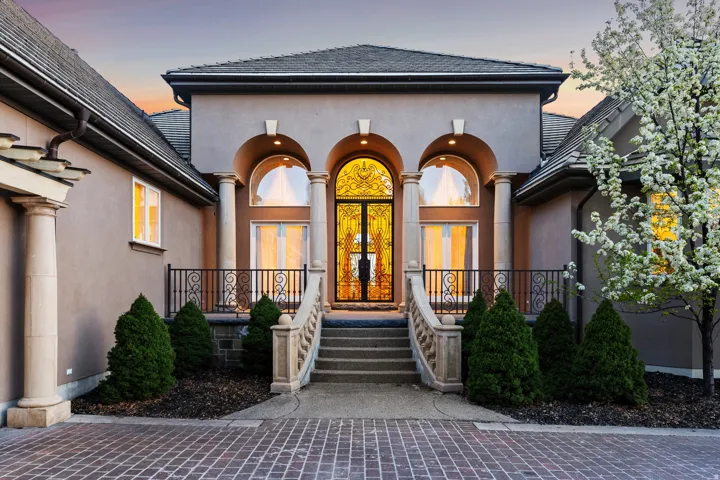 Stucco exterior featuring a tiled roof and arched entryway