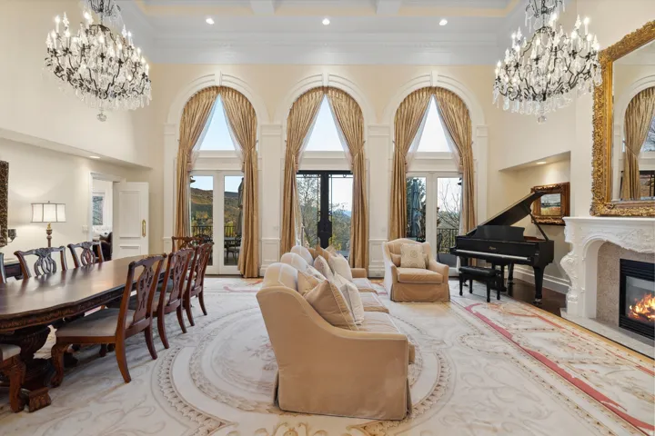 Arched windows with transoms, coffered ceilings, two chandeliers, a decorative fireplace, and double French doors