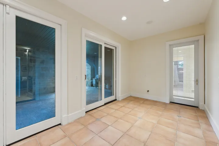 Terracotta-style tile flooring, recessed ceiling lighting, and multiple glass-paneled doors