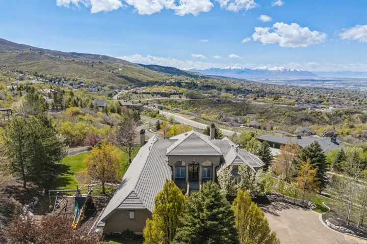 Expansive property featuring a tiled roof, multiple chimneys, and a paved driveway