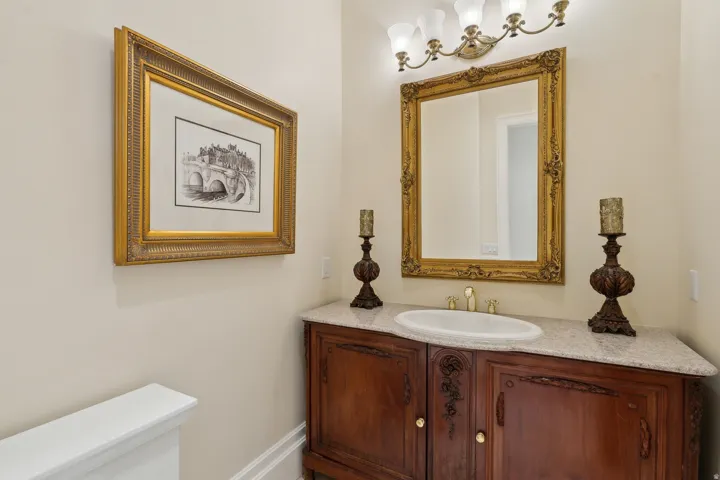 Custom wood-finish vanity with an integrated sink, polished countertop, and an ornate framed mirror