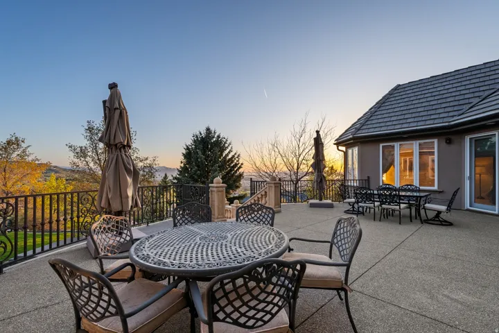 Expansive concrete patio with decorative wrought iron railing, stucco exterior, and multi-pane windows