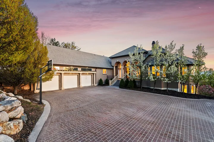 Paver driveway leading to a three-car garage