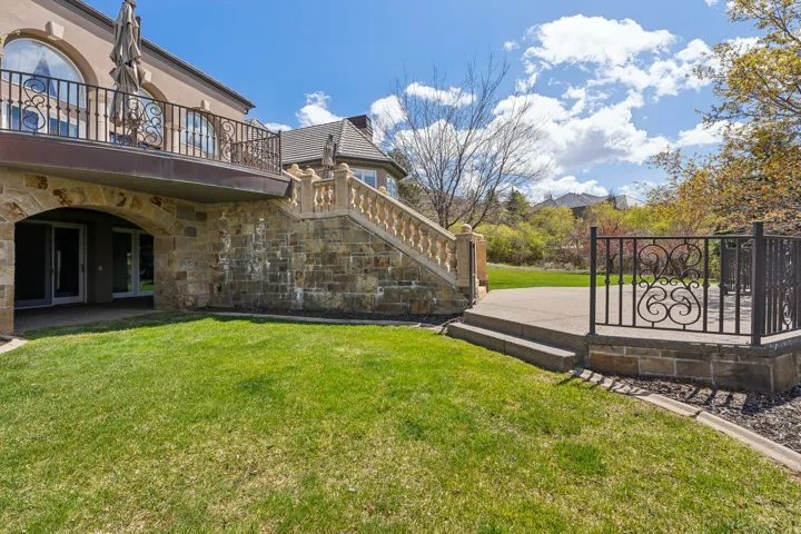 Stone exterior with an arched entryway, upper-level balcony with ornate iron railing, and exterior staircase