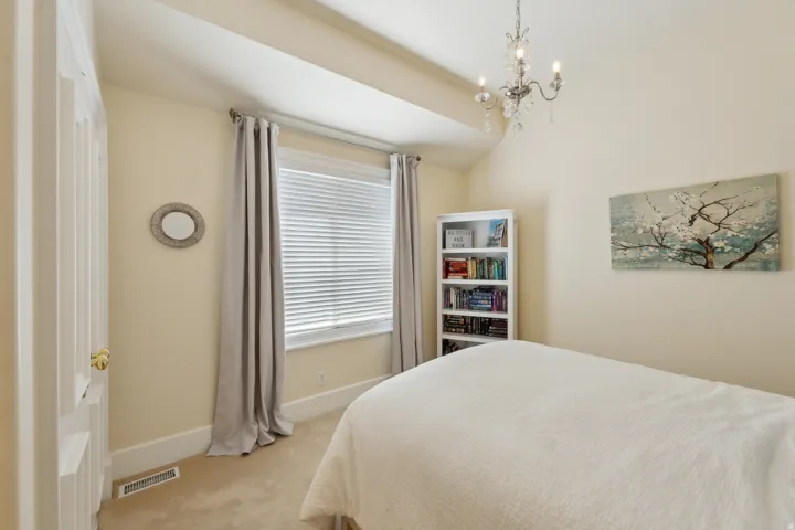 Vaulted ceiling with chandelier, window with blinds, paneled door with brass hardware, built-in shelving, and carpeted flooring