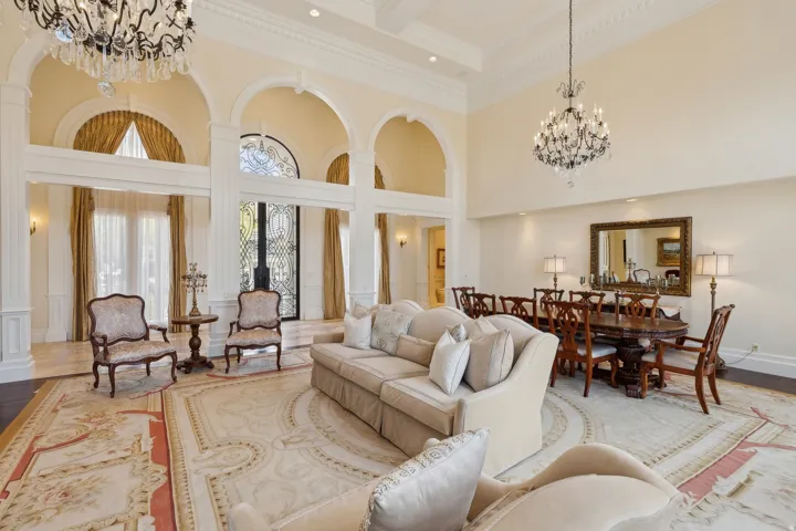 Two-story entry foyer with arched openings, ornate chandeliers, decorative ceiling molding, and a wrought iron entry door