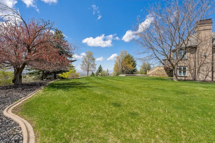 Expansive lawn featuring mature trees and a stone-clad exterior