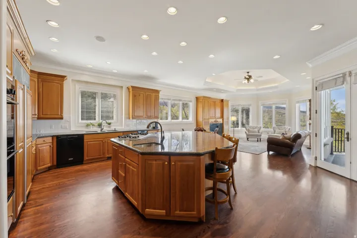 Expansive kitchen featuring wood-finish flooring, custom cabinetry, a large center island with seating, and integrated appliances