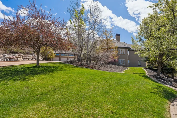 Expansive green lawn with mature trees and landscaped planting beds