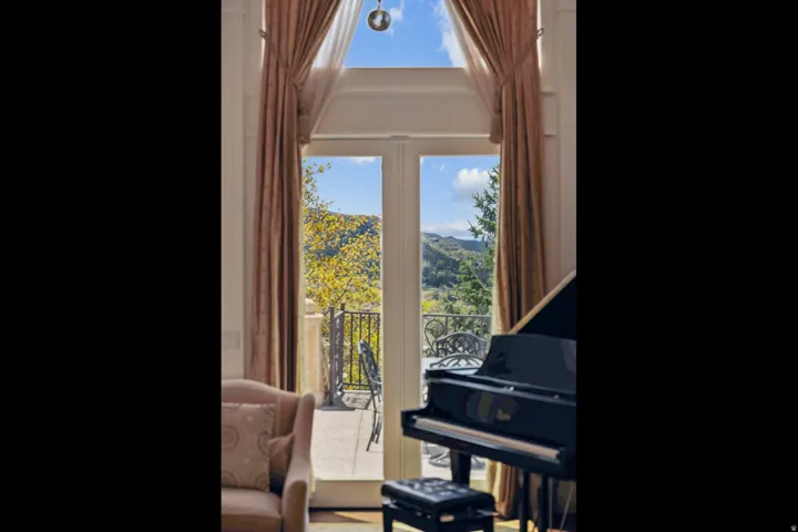 Double French doors open to a balcony featuring an ornamental iron railing