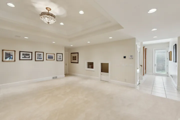 Recessed lighting, tray ceiling, crystal chandelier, neutral carpeting, and tile flooring