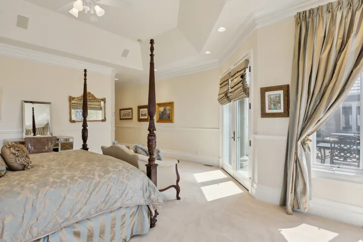 Vaulted ceiling with recessed lighting, crown molding, double French doors, large window, and light-toned carpeting