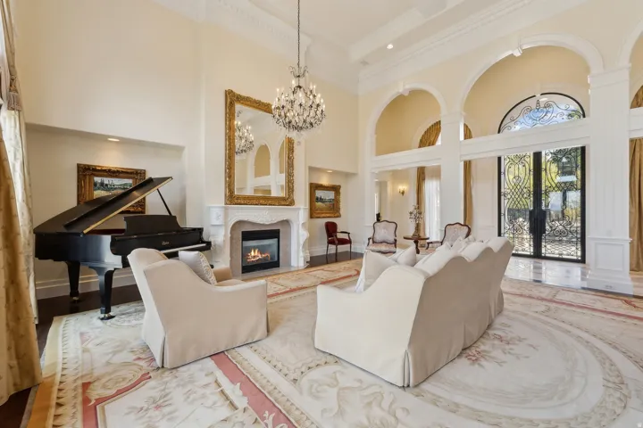 Soaring ceilings with decorative crown molding, a decorative fireplace with a mantel, and arched doorways with custom ironwork