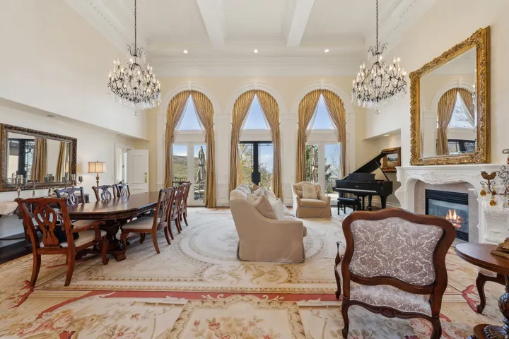 Living area featuring a grand fireplace, two crystal chandeliers, three arched French doors, and coffered ceilings