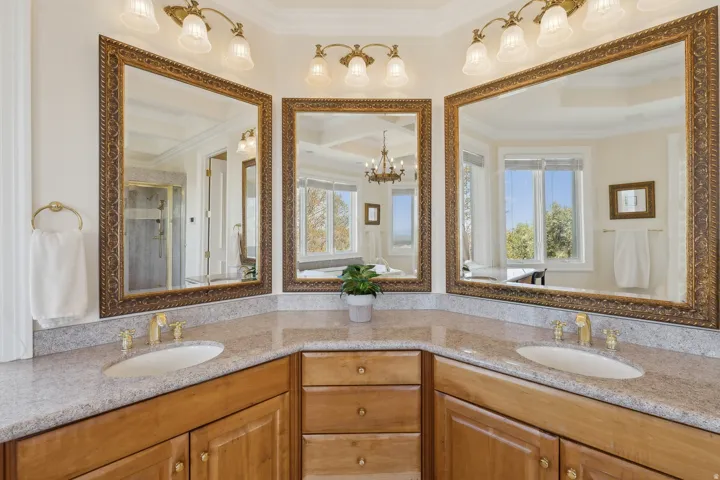 Corner vanity with dual undermount sinks, stone countertops, and wood cabinetry
