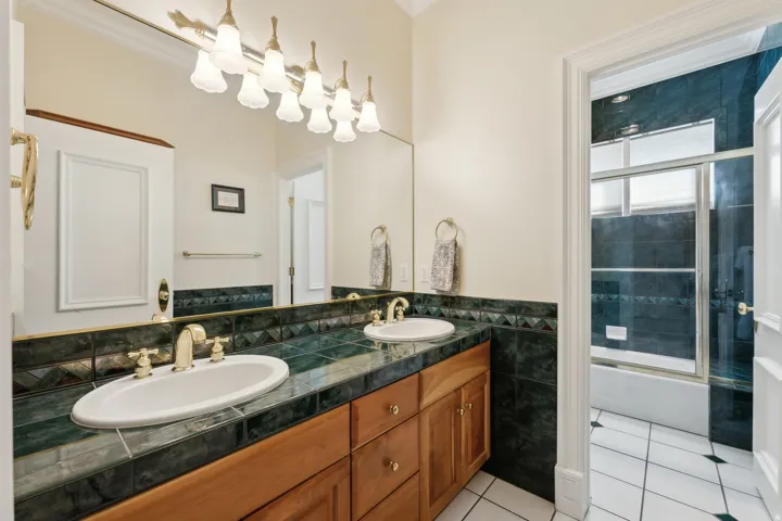 Double vanity with wood cabinetry, tile countertop, and undermount sinks