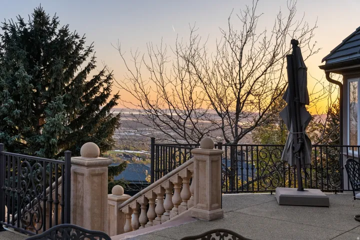 Expansive exterior patio with decorative wrought iron railing, stone balustrade, and paved surface