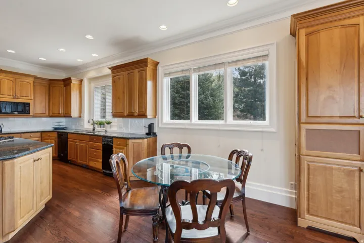 Kitchen featuring wood-finish cabinetry, dark countertops, a tile backsplash, and recessed lighting
