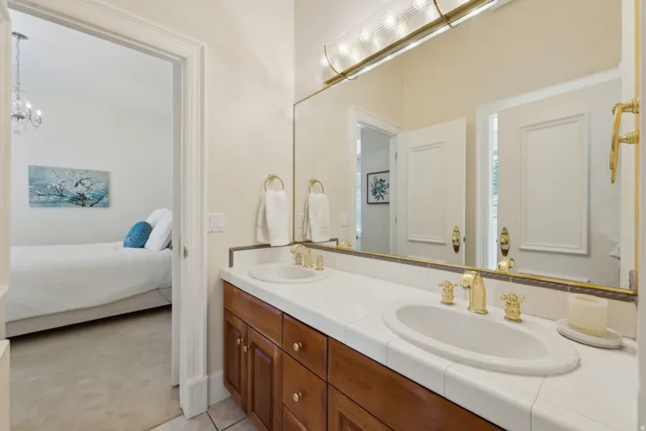 Dual vanity with tile countertop, brass-finish fixtures, and a large mirror
