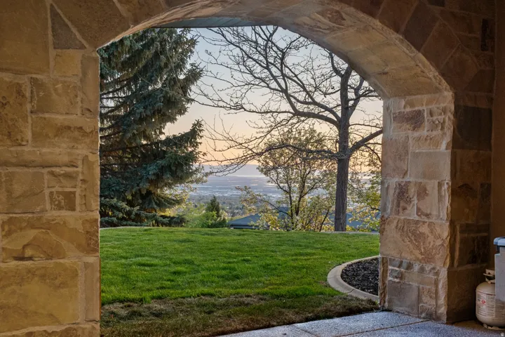 Stone archway with natural stone masonry, concrete patio, and a manicured lawn