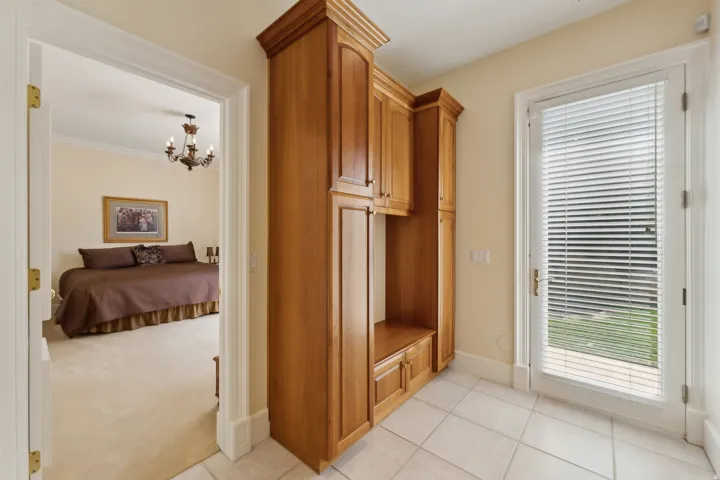Built-in wood cabinetry with crown molding, tiled flooring, and a glass-paneled door with integrated blinds