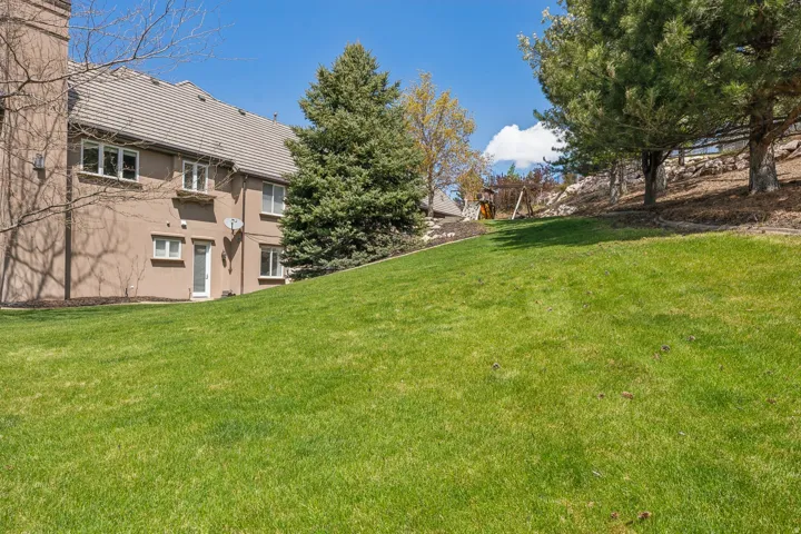 Expansive, manicured lawn with mature trees and a stucco exterior
