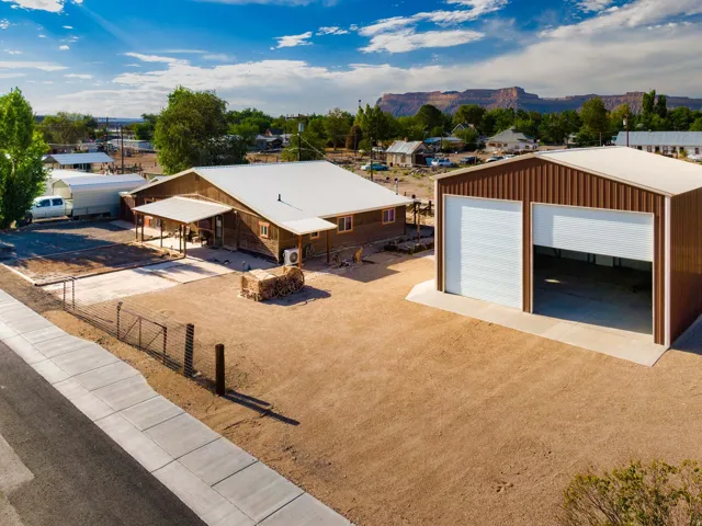 Brown vertical metal siding structure with two white roll-up garage doors, concrete pad, and metal roof