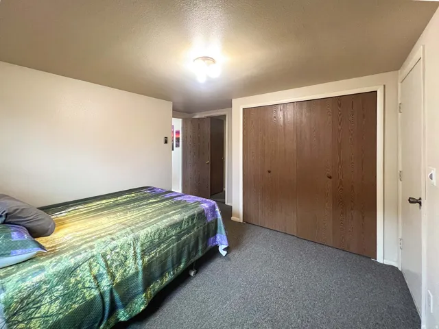 Recessed lighting with a ceiling-mounted fixture, wood-grain bi-fold closet doors, and dark gray carpet flooring