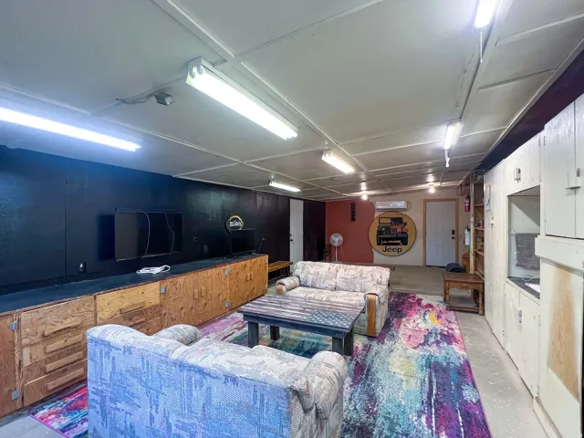 Built-in storage cabinetry, track lighting, ceiling-mounted fluorescent lighting, and a wall-mounted air conditioning unit are featured within this versatile space