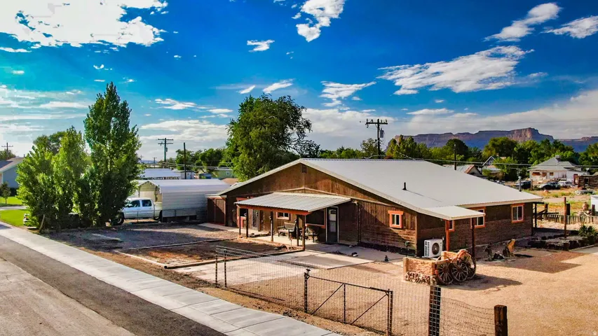 Ranch-style residence featuring a metal roof, wood siding, covered patio, and fenced front yard