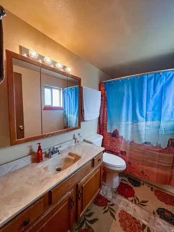 Vanity with wood-finish cabinetry, integrated sink, and light-toned countertop