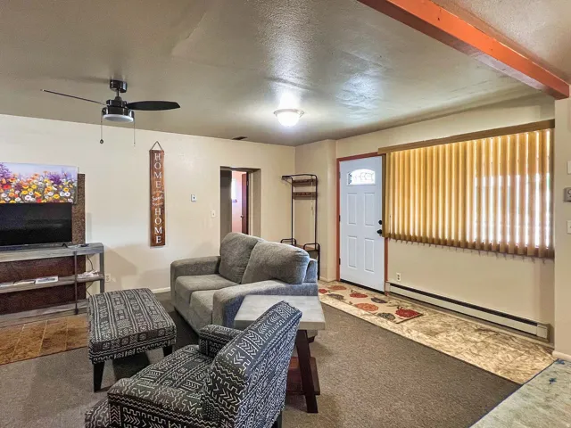 Entry door with half-lite window, vertical blinds, and a ceiling fan