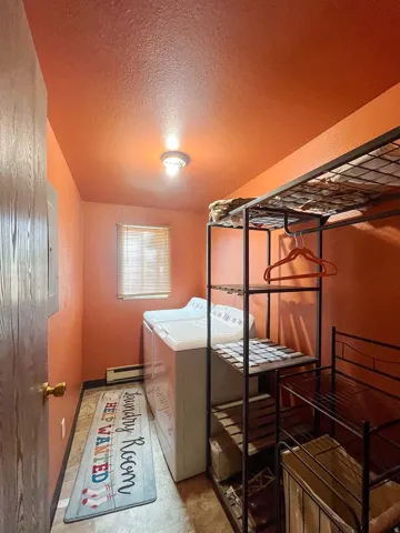 Utility space with overhead lighting, a window with blinds, and built-in shelving