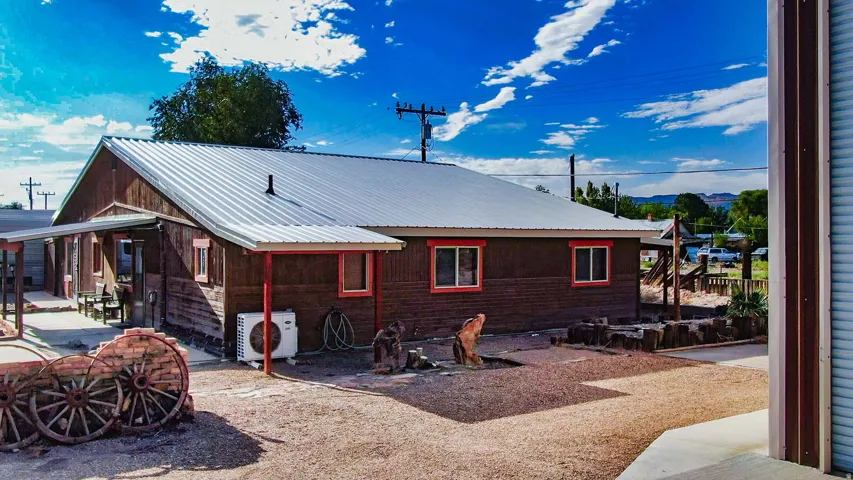 Wood-sided exterior with a metal roof and red trim windows