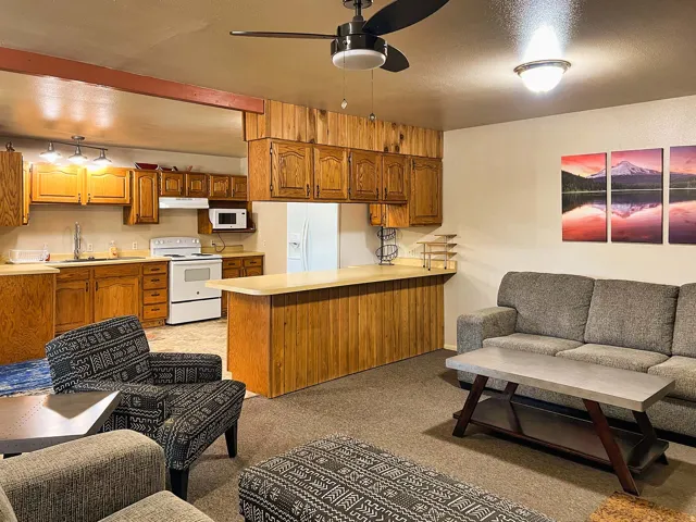 Open concept living area with a kitchen featuring wood cabinetry, white appliances, and a peninsula with a breakfast bar